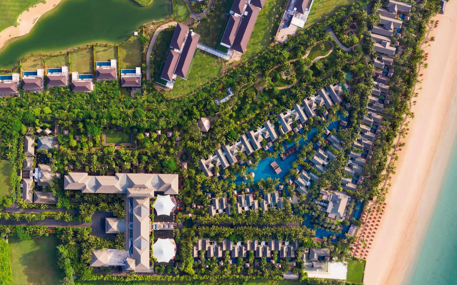 空拍的海濱度假村，泳池與花園緊鄰一長條沙灘