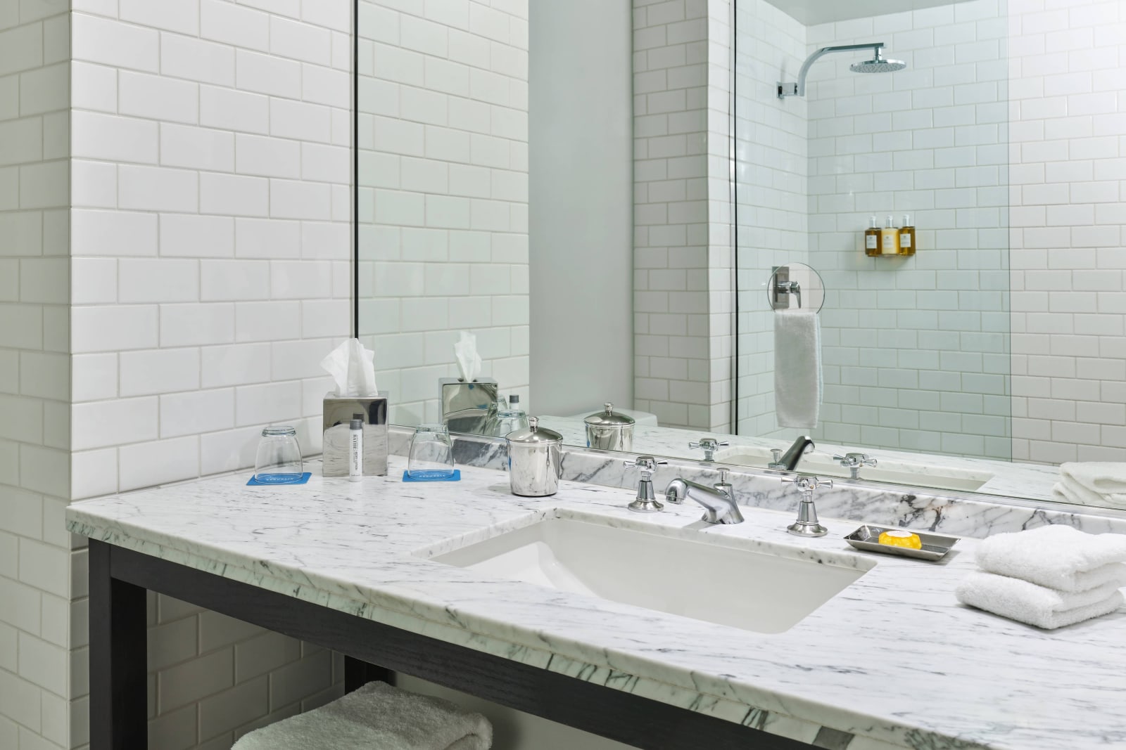 Bathroom counter and wide mirror with a glass enclosed shower behind