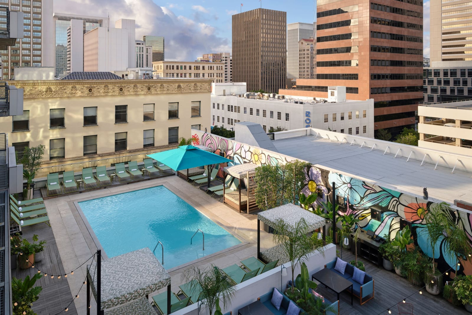 Looking down from the hotel roof over a run of low old brick rooftops with downtown office towers behind them