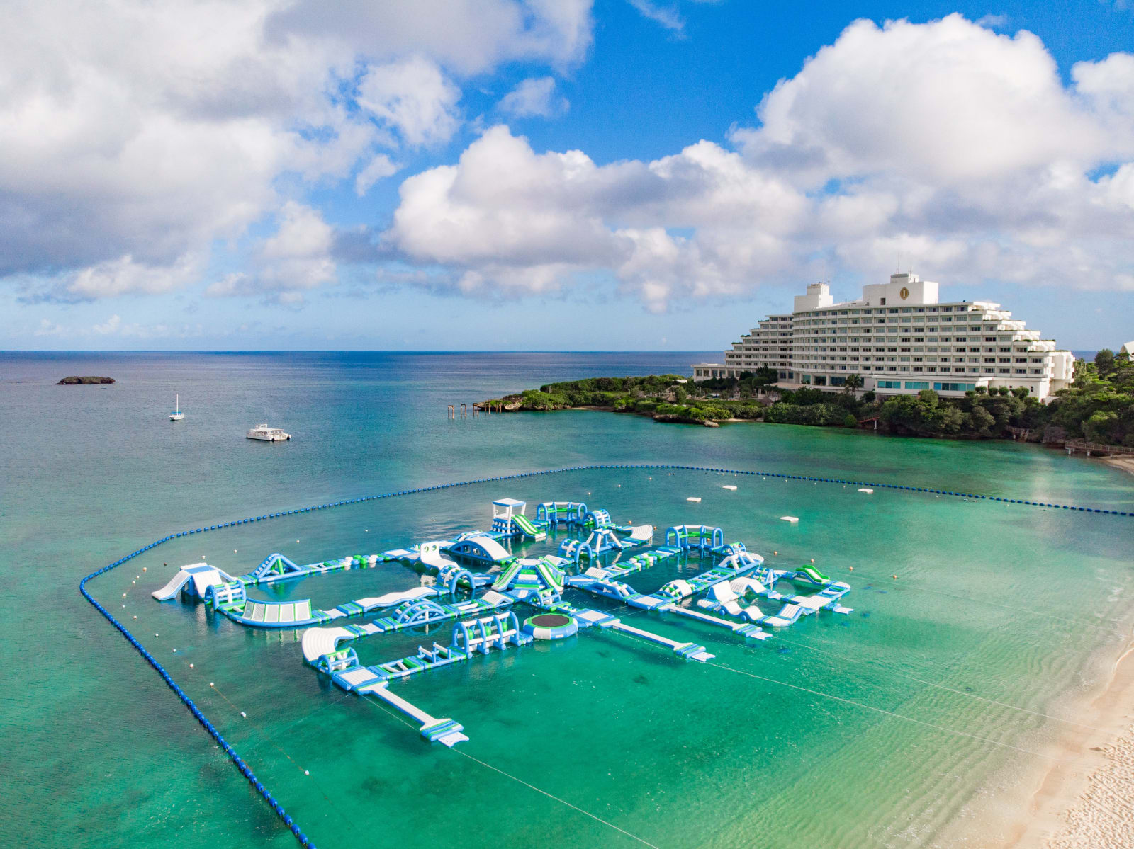 Large inflatable water park floating on the sea, made up of several linked zones