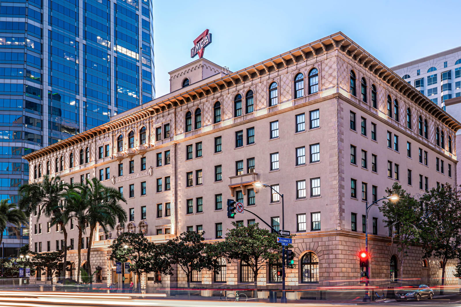 Six story Italian Renaissance Revival building on a corner with a glass tower behind it