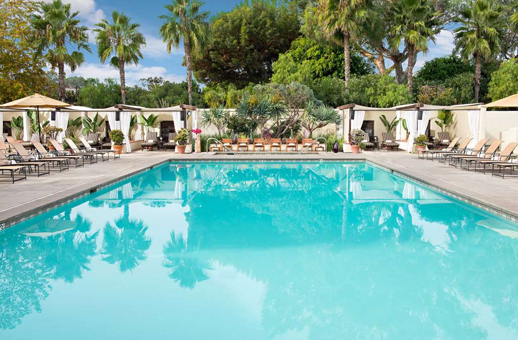 Rectangular pool enclosed by palms and Spanish style buildings