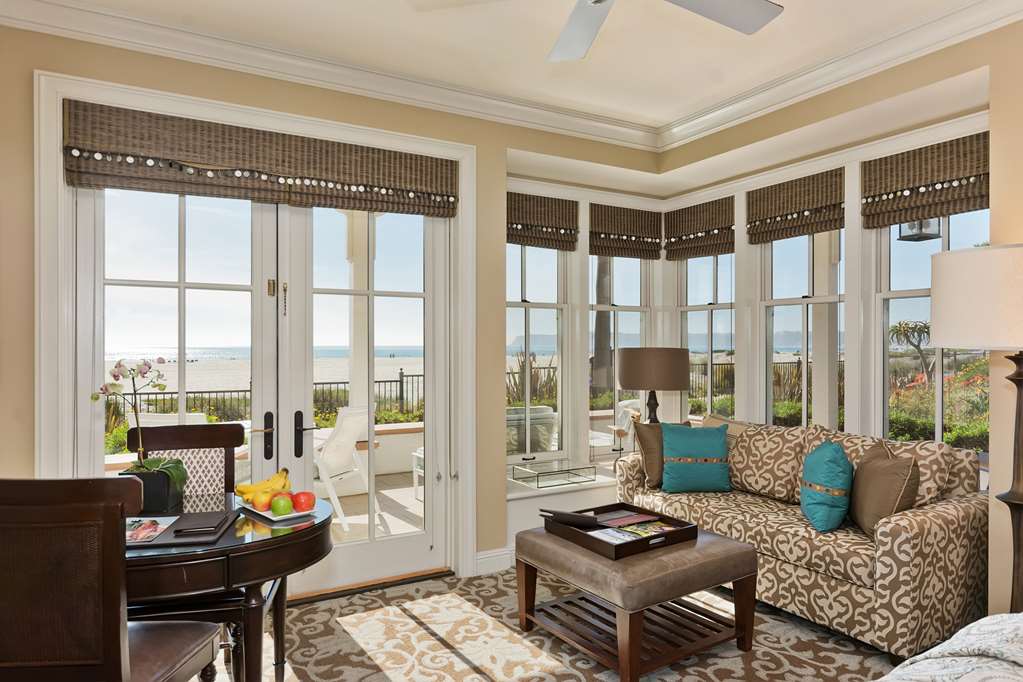 Living room with windows on three sides and wooden blinds, beach and ocean beyond