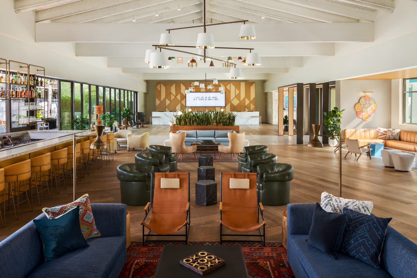 Lobby with low sofas, a wooden bar, starburst light fittings and full height glazing