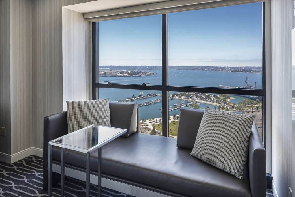 Guest room with floor to ceiling glass and a window bench looking over San Diego Bay