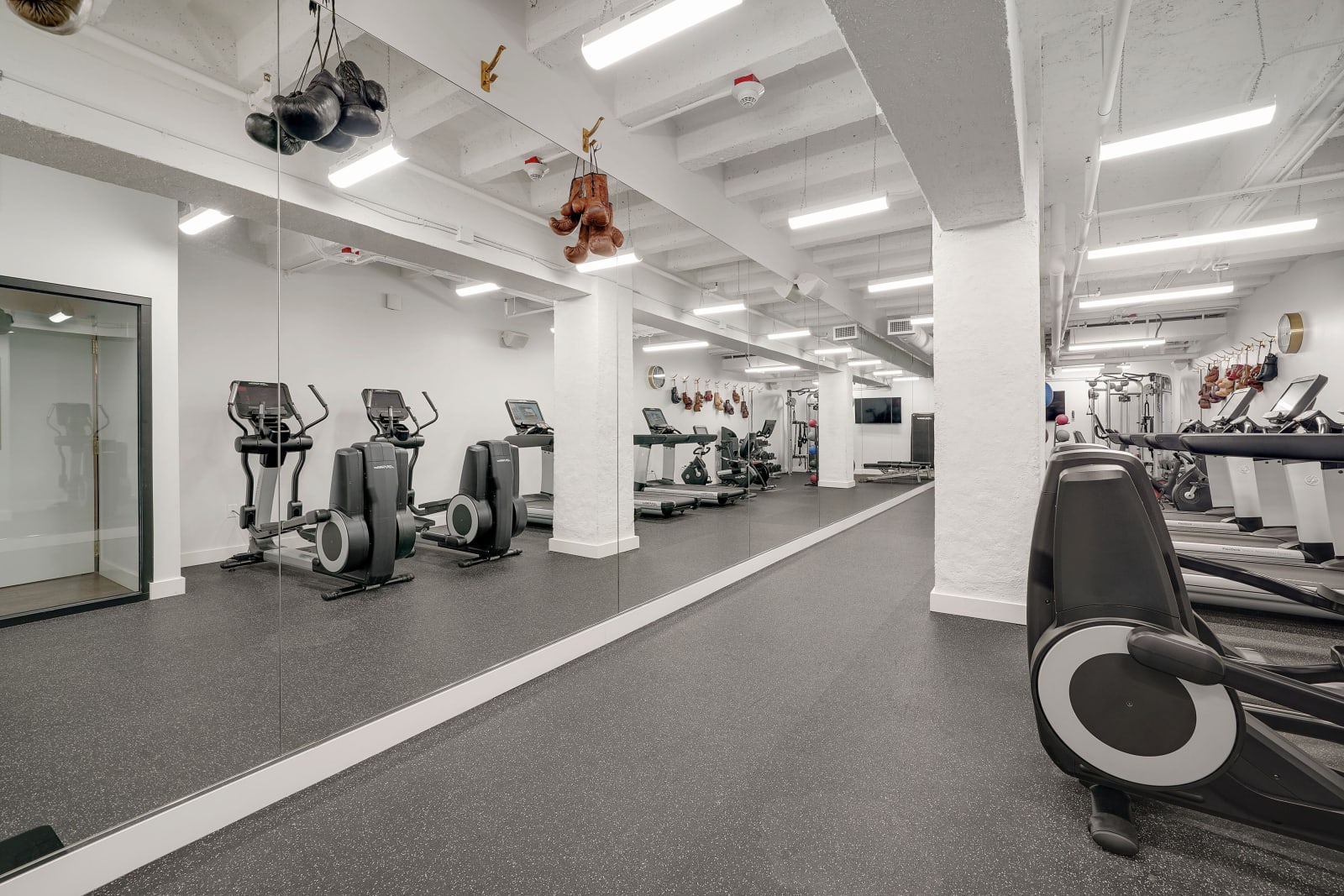 Fitness room with rows of equipment beneath a ceiling of concrete arches