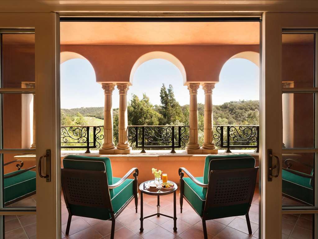 Seating on an arched loggia terrace with green canyon beyond the railing