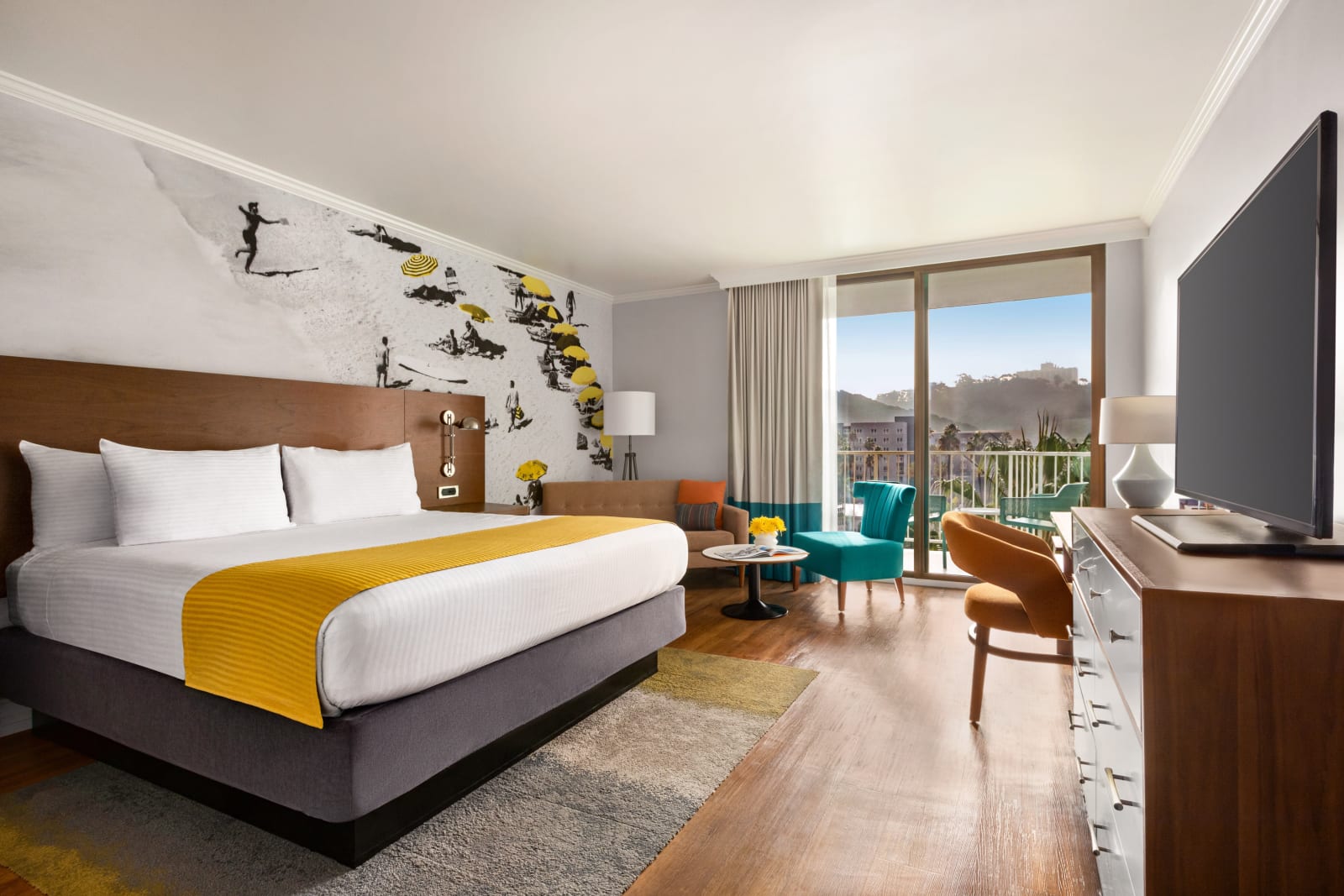 Guest room with a king bed, a yellow bed runner and a teal armchair by the window
