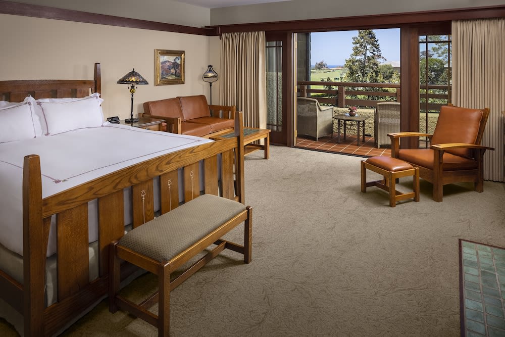 Guest room with a timber framed bed, leather armchair and a door to the outside
