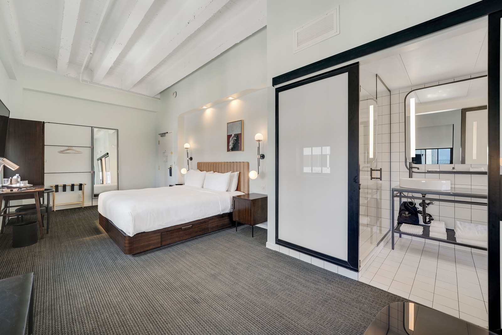Black framed sliding glass door between guest room and bathroom with the vanity visible beyond