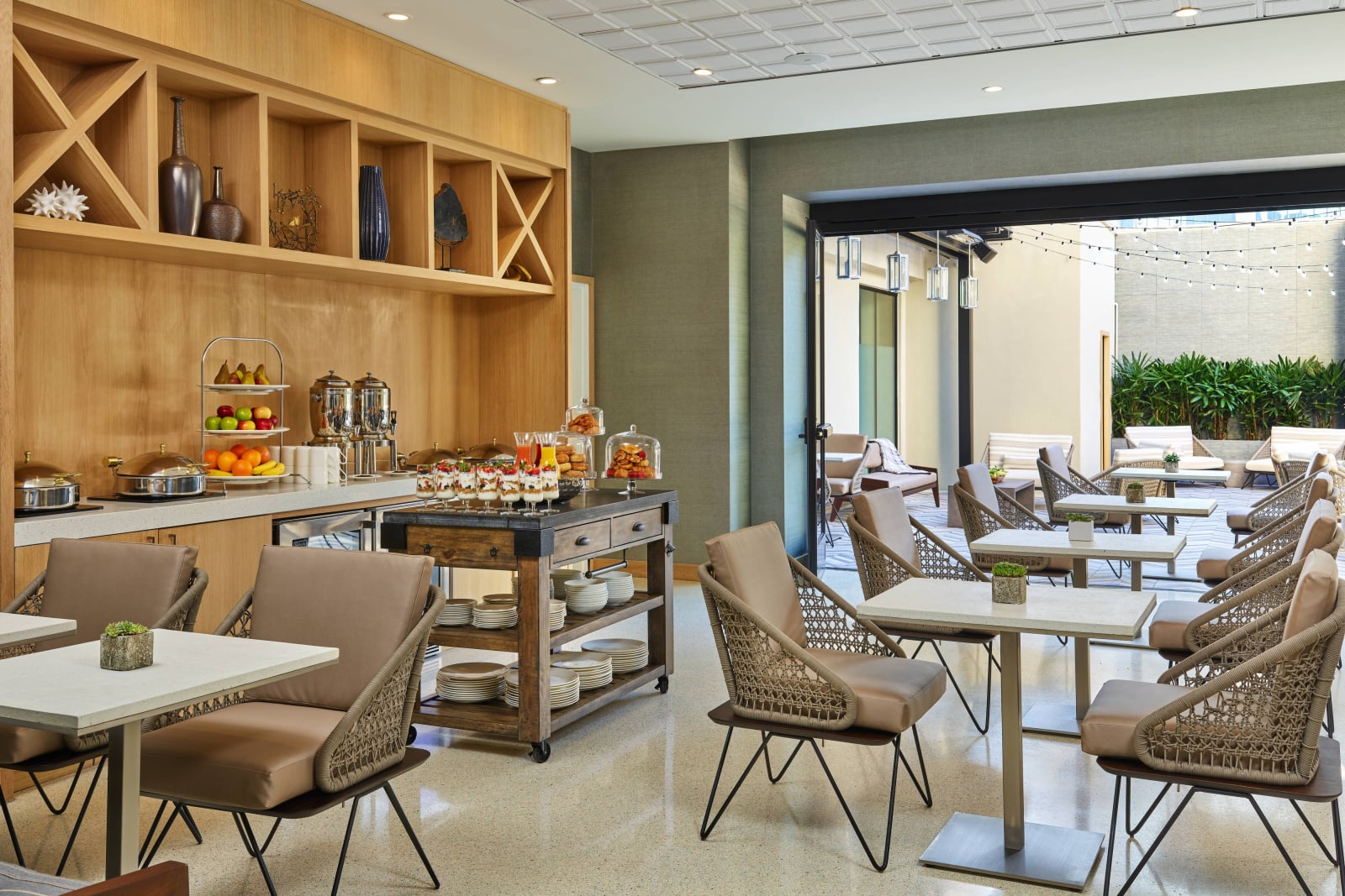 Dining area with wooden shelving and a pastry counter, opening toward the outdoors