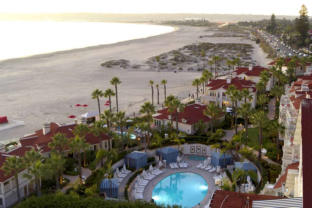 Aerial view of a long beach, rows of red tiled roofs and a circular pool