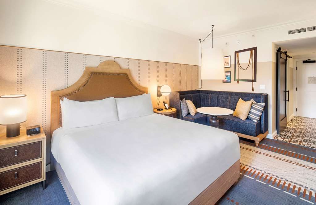 Guest room with a king bed and a deep blue built in banquette, equestrian artwork on the wall