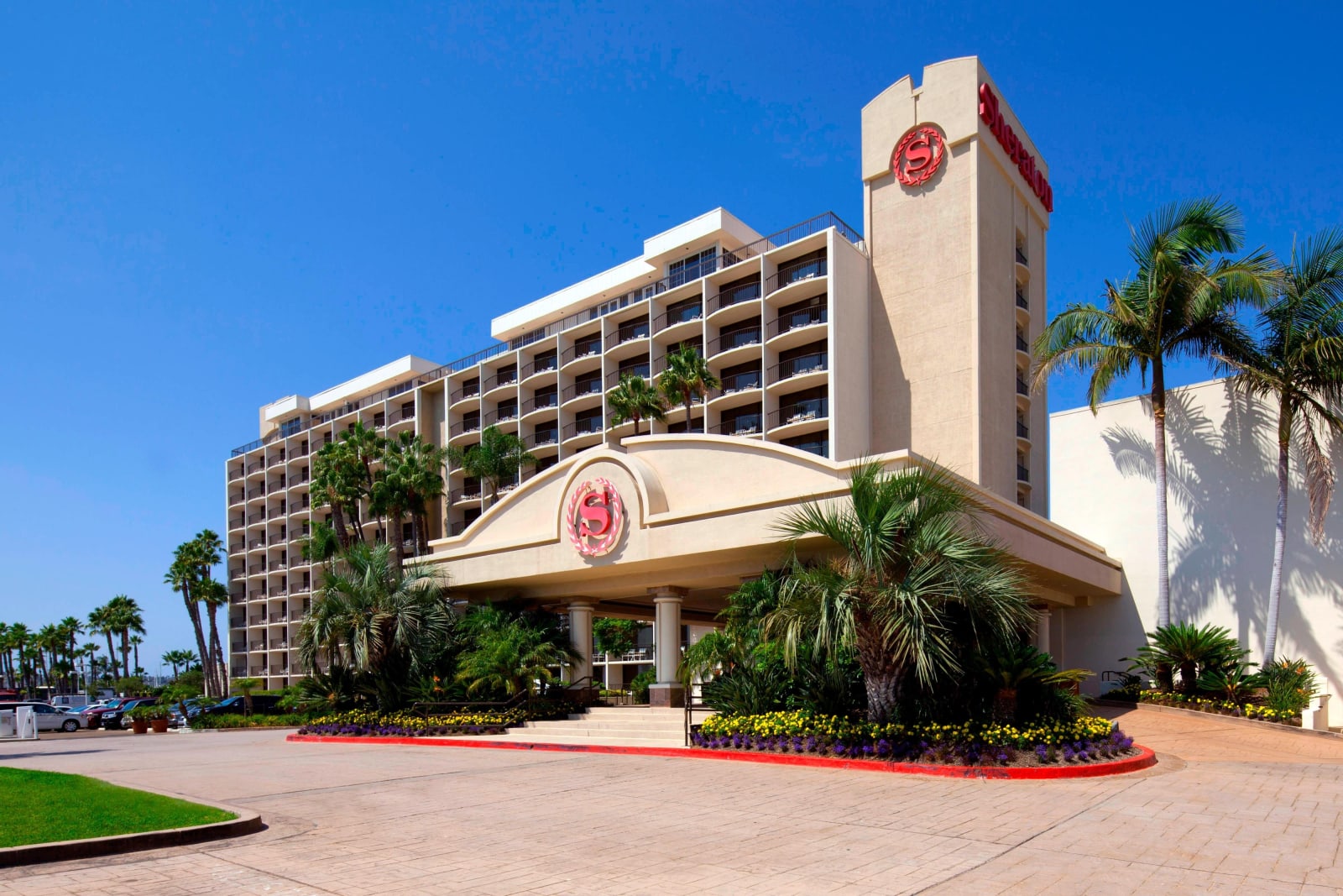 Main hotel tower and porte-cochère with palms and lawn in front