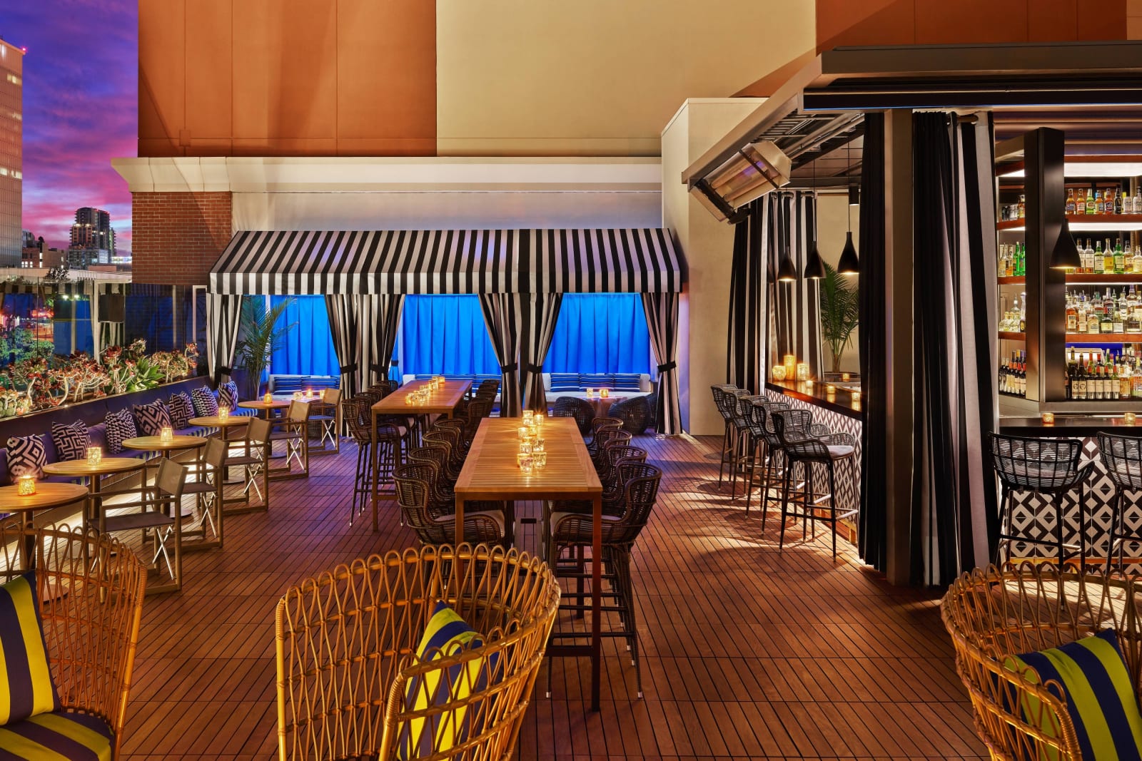 Indoor bar and long communal table under blue awnings with woven stools