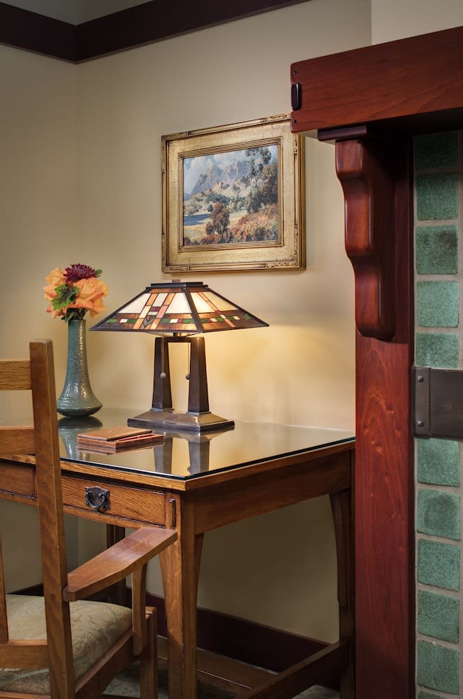 Table lamp with a leaded art glass shade beside dark joinery and a ceramic vase