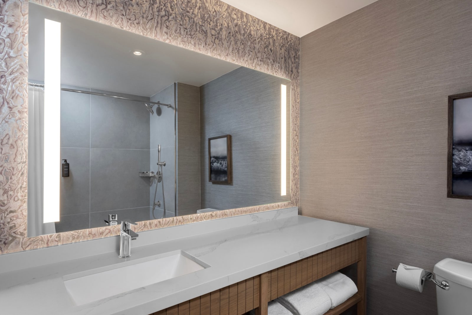 Renovated bathroom vanity with a large lit mirror