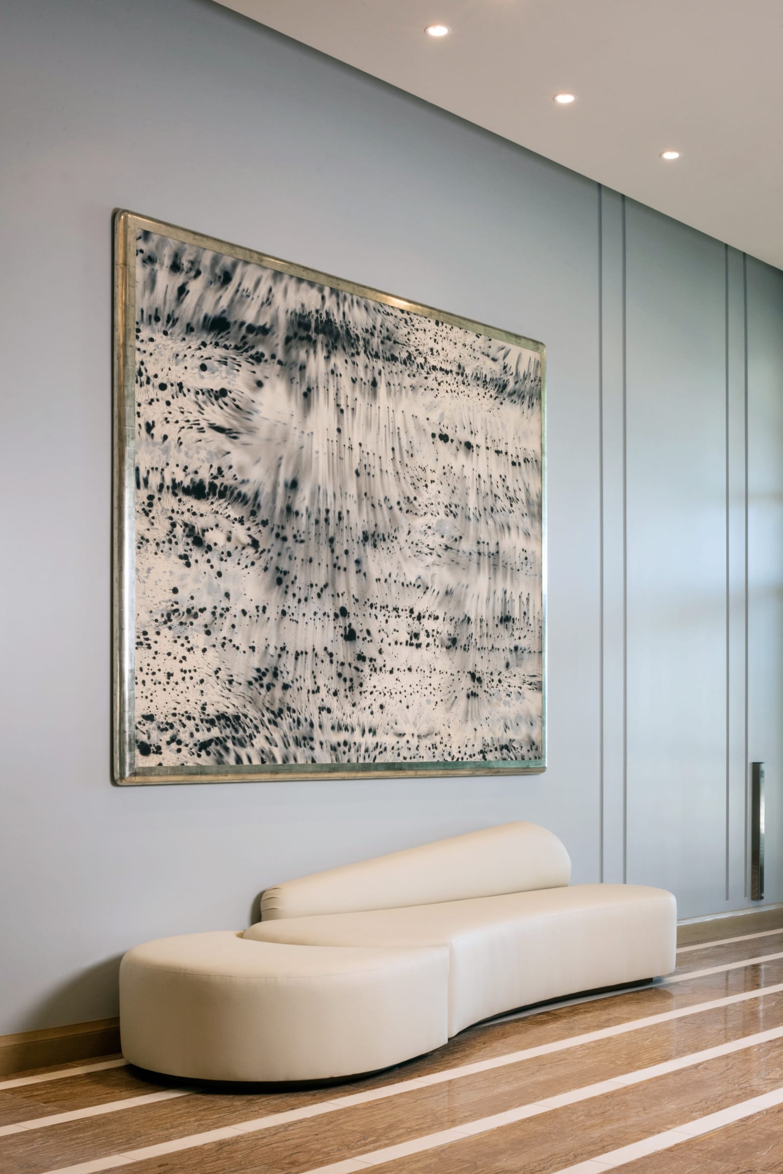 Large painting and a curved bench in a hotel public space
