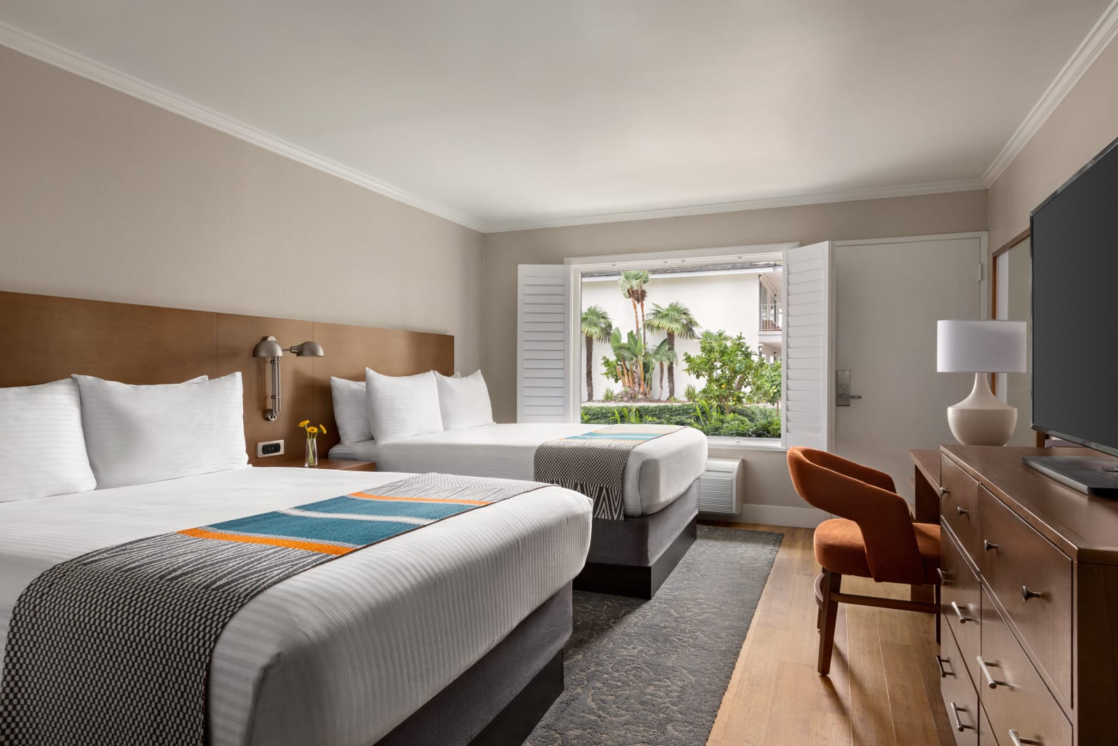 Room with two beds, timber panelling and palms outside the window