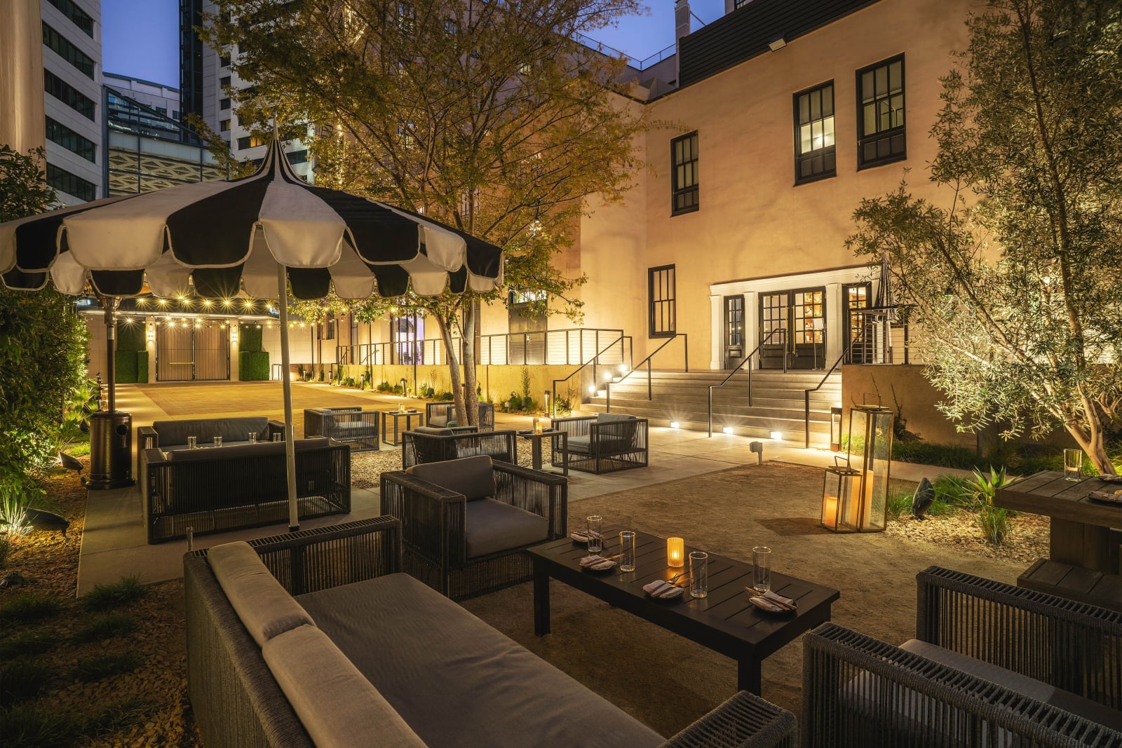 Outdoor garden at night with strings of lights, lounge seating and a historic facade behind