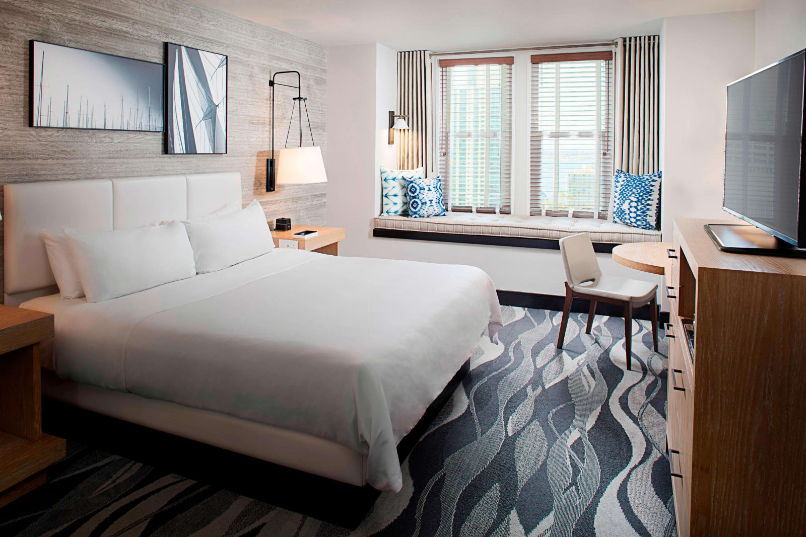 Guest room with a king bed, wave patterned carpet and a run of windows along one side