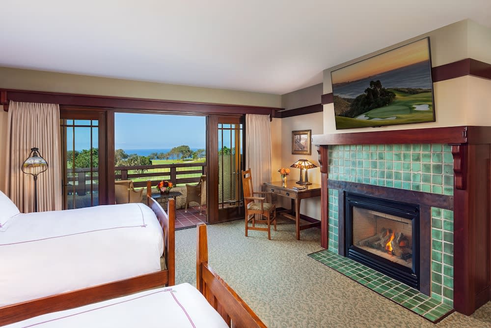 Guest room with a green tiled fireplace, timber framed bed and a door to a terrace