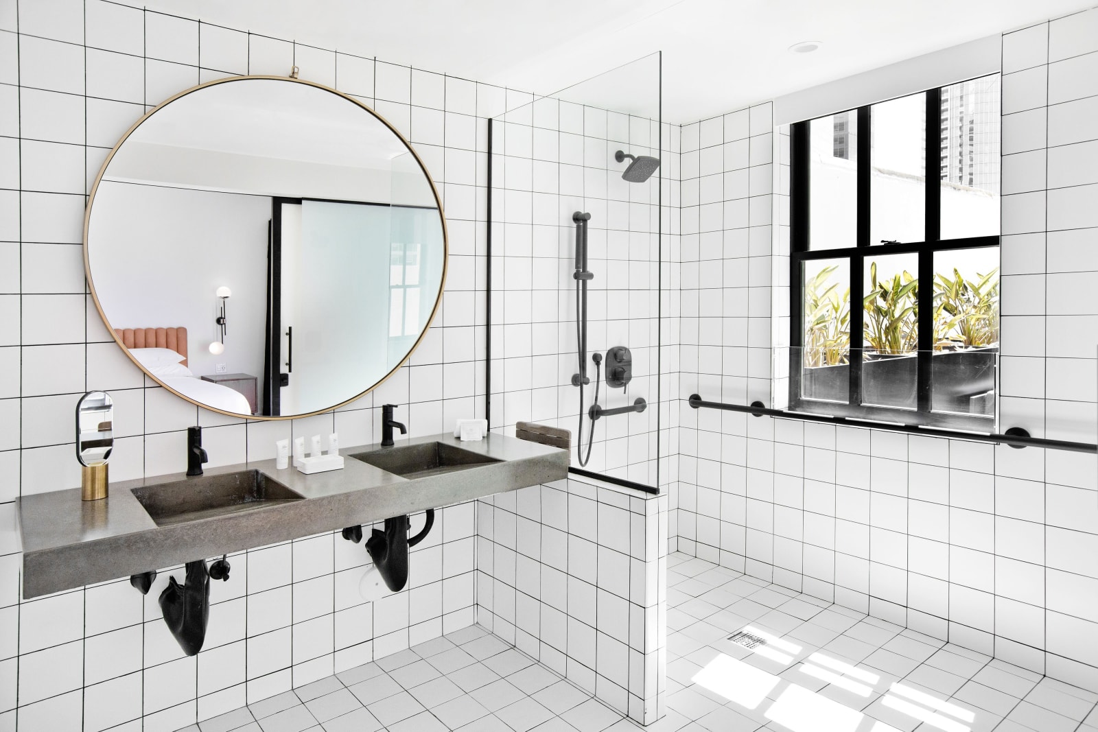 Accessible bathroom with horizontal grab bars on white tile, a double vanity and a large window
