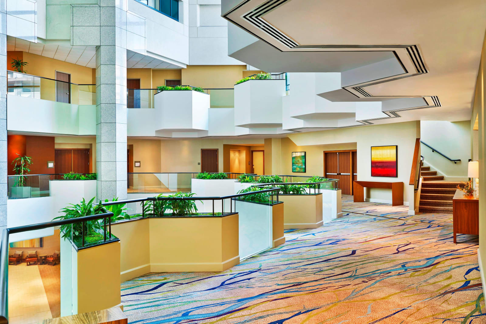 Hotel atrium with tiers of open corridors, green planting and stairs