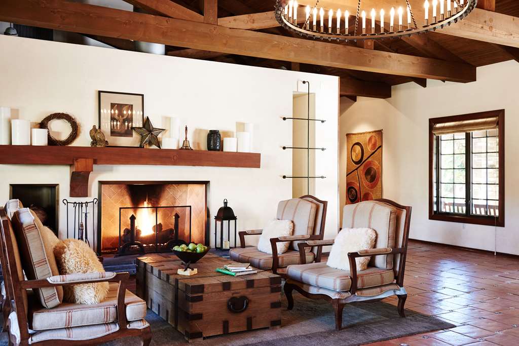 Lounge with exposed timber beam ceiling, a large fireplace and a circular iron chandelier