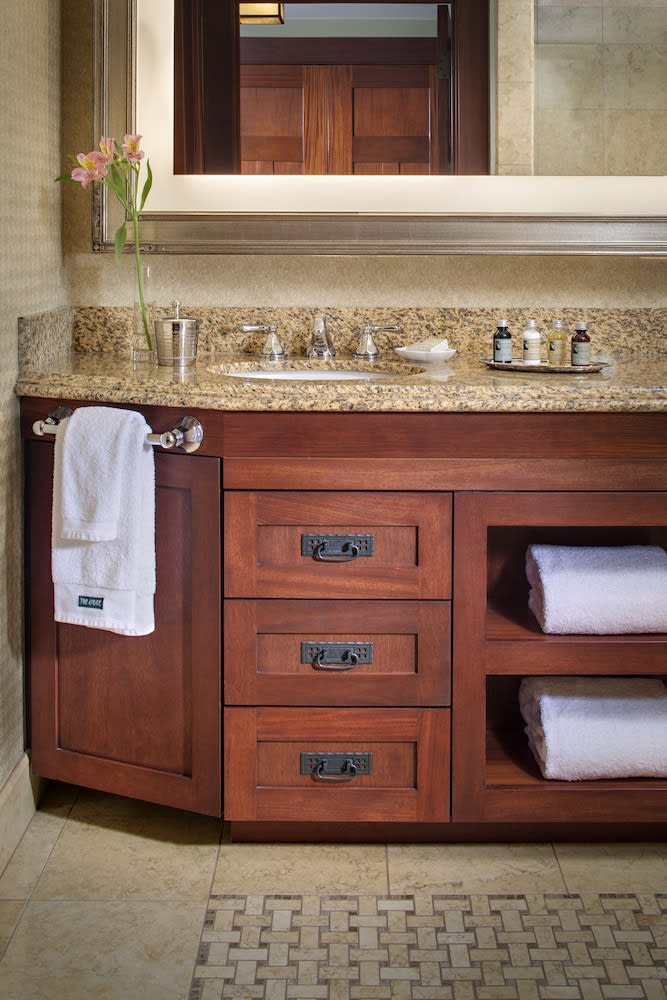 Bathroom vanity in dark joinery with a stone top and white towels