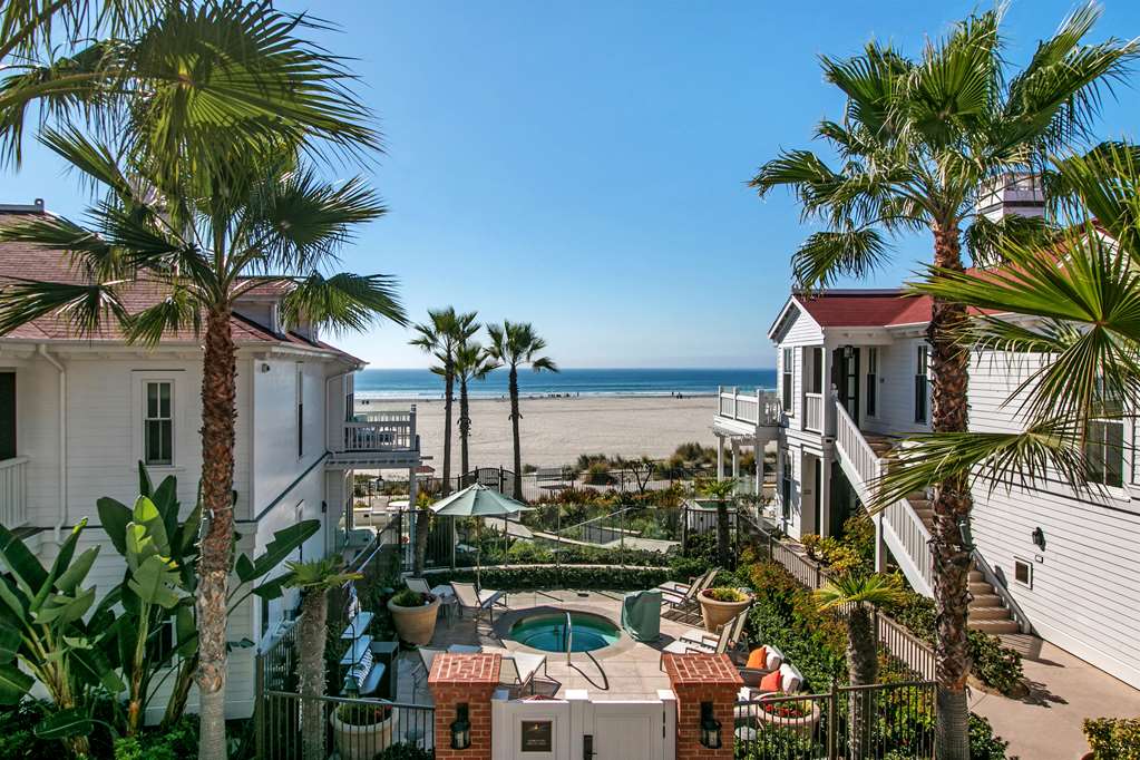 Elevated view over rows of white and red tiled cottages, palms and the beach in the distance