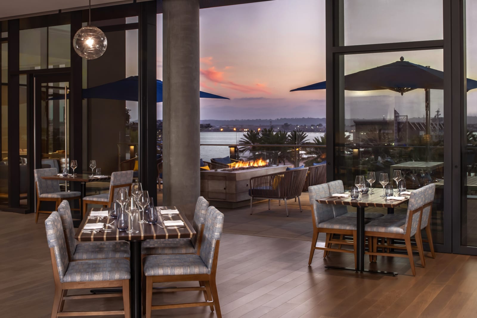 Restaurant interior with floor to ceiling glass onto the waterfront at dusk