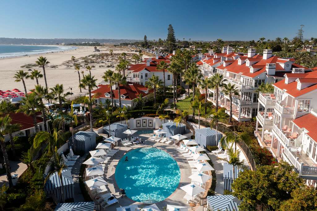Aerial view of a circular pool ringed by rows of red tiled cottages with the beach beyond