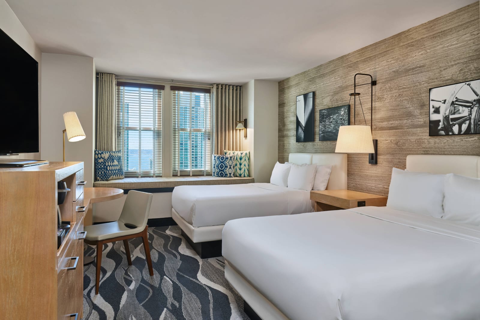 Room with two double beds, seating at the window and a desk