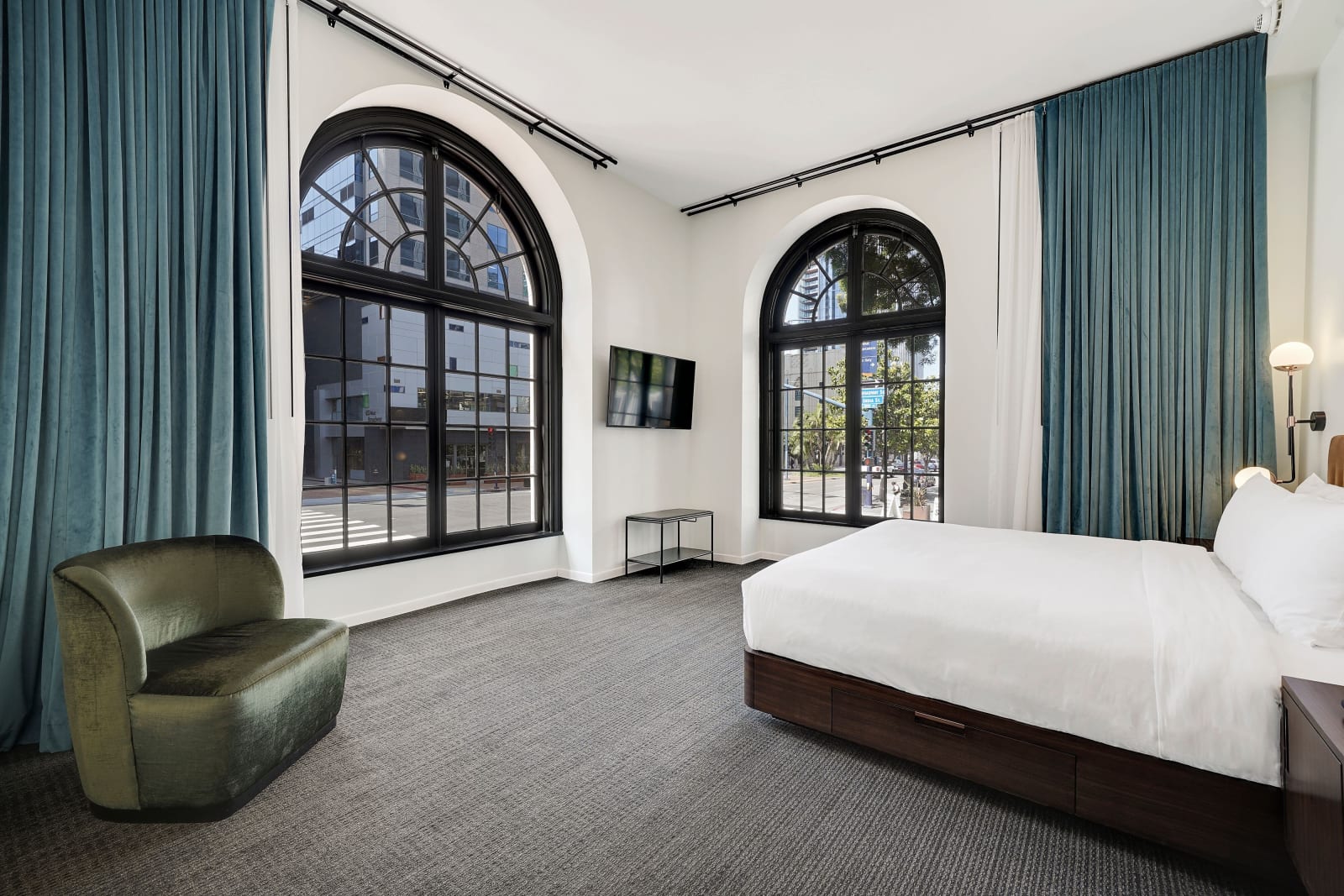 Room with two tall arched windows and green velvet armchairs against white walls