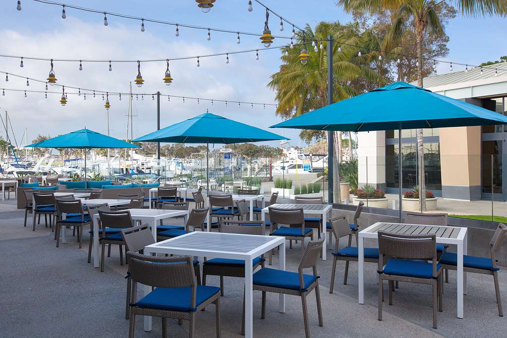 Outdoor seating on the waterfront terrace with umbrellas and the marina behind