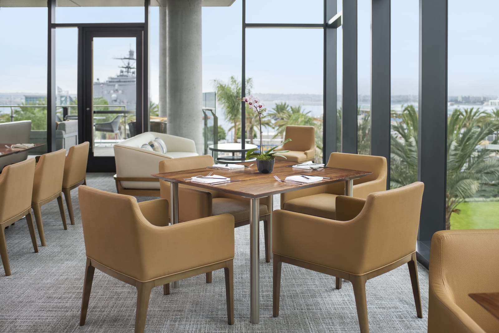 Club lounge seating area with USS Midway visible through the window