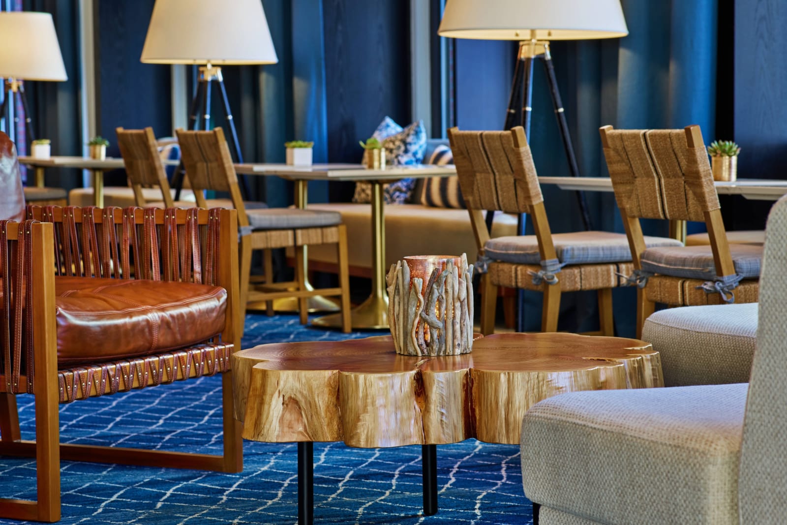 Lobby seating area with blue carpet, leather armchairs and low wooden tables