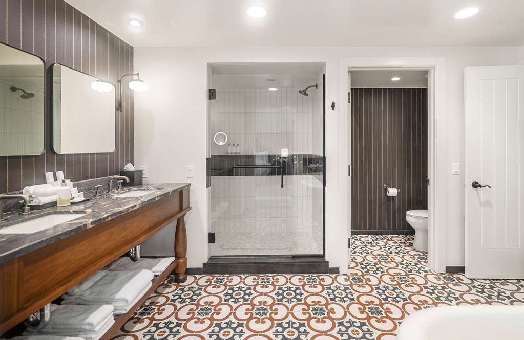 Bathroom with a double vanity, separate walk in shower and geometric patterned floor tile