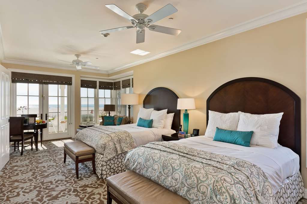 Bedroom with two large beds, a vaulted ceiling and a fan, French doors to a balcony