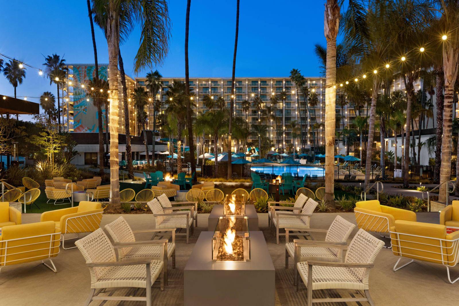 Fire pit seating at dusk with the lit pool and the tower behind