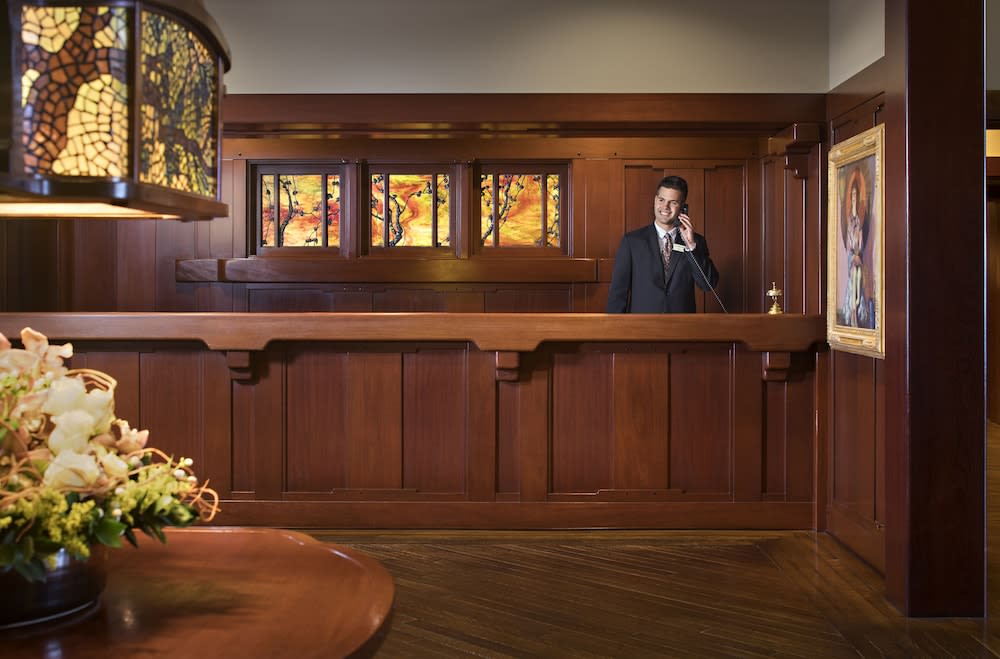 Dark timber reception desk with a row of art glass windows above