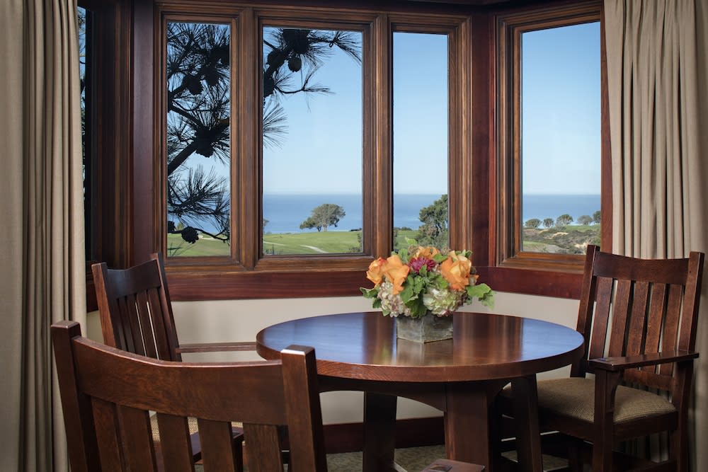 Corner window seating area in a room with trees and the sea beyond