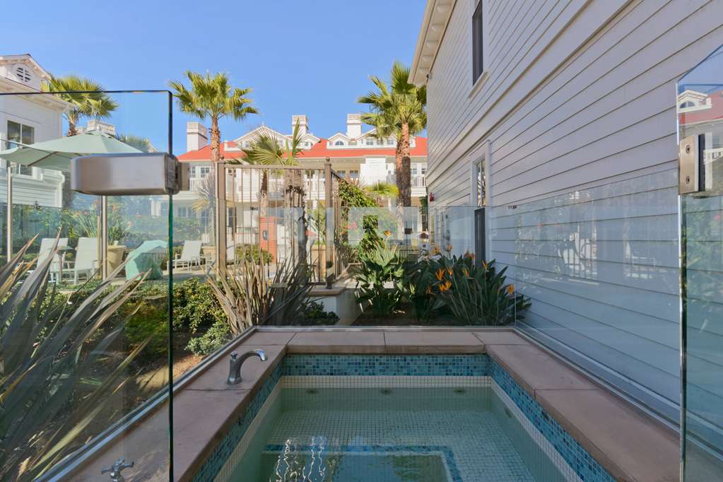 Small plunge pool between two white clapboard buildings with glass fencing and palms