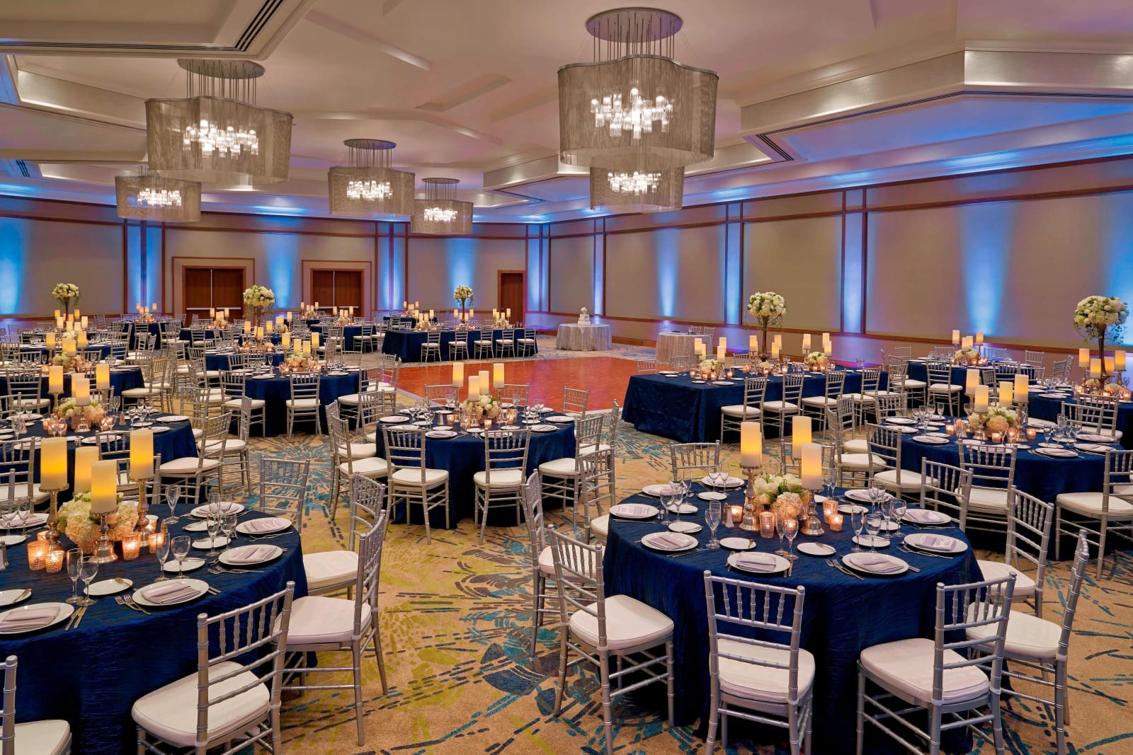 Ballroom laid out with round tables under blue uplighting