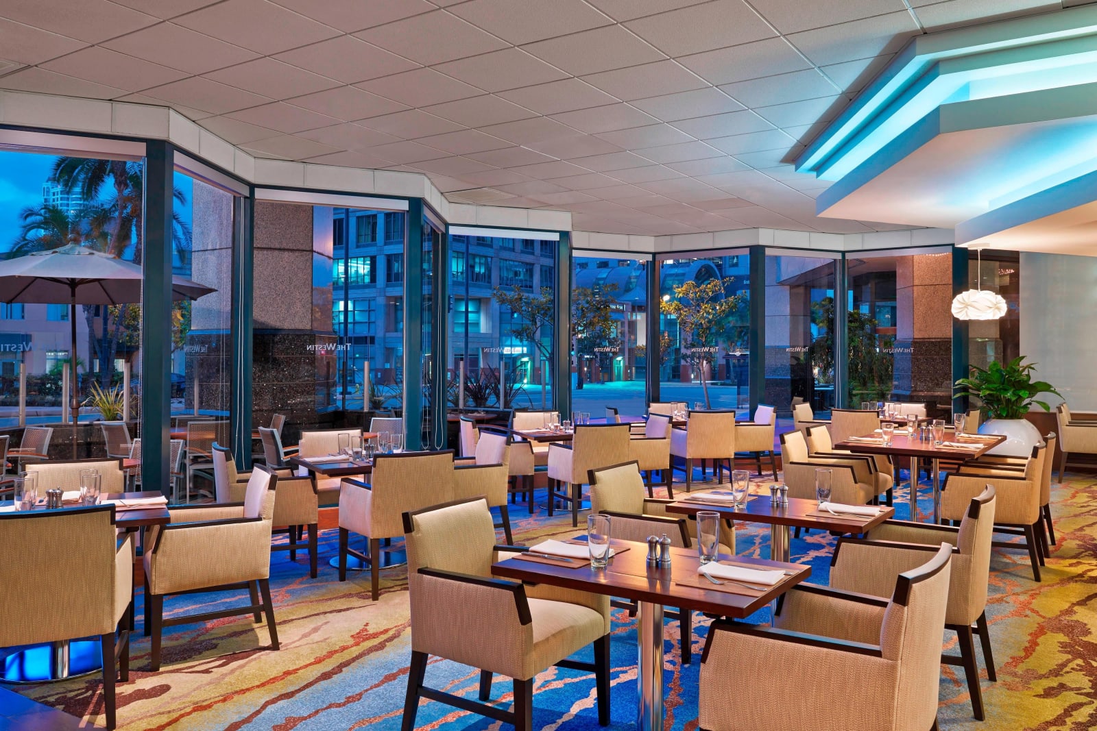 Restaurant interior with a wall of windows and blue evening light outside